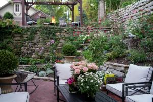 a garden with chairs and flowers and a stone wall at Inn at Rose Hall in Eureka Springs