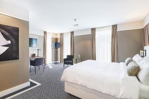 a hotel room with a white bed and a desk at Hotel Nassau Breda, Autograph Collection in Breda