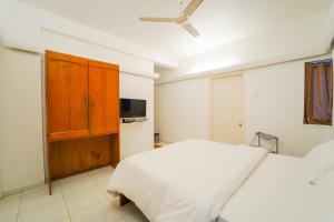 1 dormitorio con 1 cama blanca y TV en The Signature Crest, en Panchgani