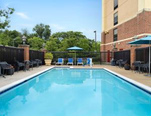 Hampton Inn & Suites Arundel Mills/Baltimore في هانوفر: مسبح وكراسي وطاولات ومبنى