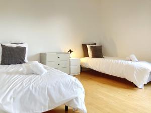 um quarto com 2 camas com lençóis brancos e uma cómoda em Tow-Bedroom Apartment Located In The Beautiful City Of Fredericia em Fredericia