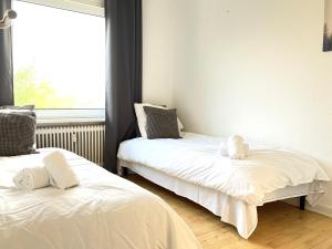 um quarto com 2 camas com lençóis brancos e uma janela em Tow-Bedroom Apartment Located In The Beautiful City Of Fredericia em Fredericia