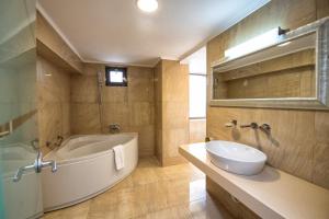 bagno con vasca, lavandino e specchio di Hotel Roman by Dumbrava Business Resort a Roman