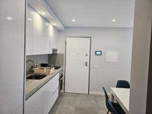 una cocina con armarios blancos y fregadero en Apartment Dona Vitória - Monte Gordo Beach, en Monte Gordo