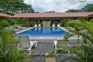 een zwembad met 2 stoelen en een gebouw bij Hotel D'Lucia - Quebrada Ganado, Jaco, Costa Rica in Puntarenas