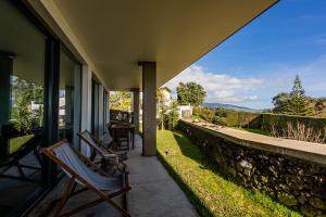 eine Veranda mit 2 Stühlen und einer Steinmauer in der Unterkunft Quinta das Camélias - Açores in Ponta Delgada