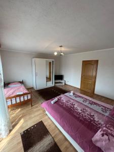 a bedroom with two beds and a pink comforter at Apartmani Hadžić in Živinice