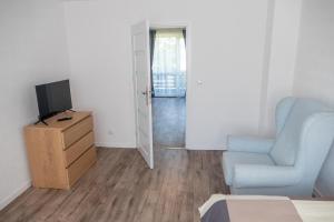 a living room with a blue chair and a television at FeWo in Radekow 3 in Mescherin