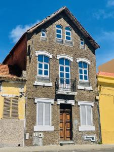 un edificio de ladrillo marrón con ventanas blancas y una puerta en KAZARÃO DI MAVETE - Guesthouse, en Praia