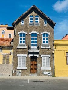 un edificio de ladrillo marrón con ventanas blancas y una puerta en KAZARÃO DI MAVETE - Guesthouse, en Praia