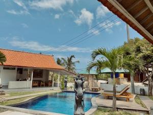 - une piscine avec une statue en face d'une maison dans l'établissement Blue Sky Villa Ceningan, à Nusa Lembongan