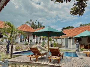 - deux chaises et un parasol à côté de la piscine dans l'établissement Blue Sky Villa Ceningan, à Nusa Lembongan