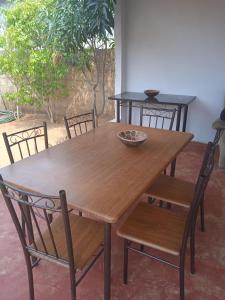 a wooden table and chairs with a bowl on top at Sunshinevibe guest house in Kasane