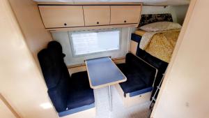 Habitación pequeña con 2 sillas, 1 cama y ventana en Camping-car, en Vitry-le-François