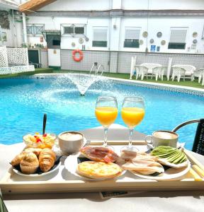 un vassoio di cibo e due bicchieri di vino accanto alla piscina di Hostal Avenida Andalucia - Solo Adultos a Siviglia