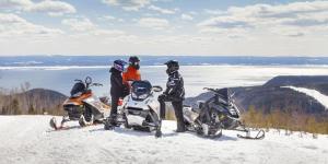 drei Leute stehen im Schnee neben zwei Motorrädern in der Unterkunft Auberge Boréale de Charlevoix in Petit-Saguenay