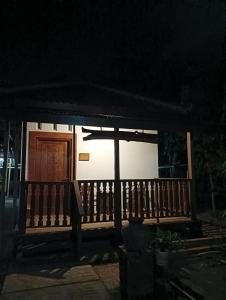 un porche de una casa por la noche con una puerta de madera en Griya Sukatno, en Magelang