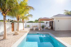 une villa avec une piscine et des palmiers dans l'établissement Appartement James, à Jan Thiel