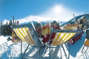 Dos chicas están sentadas en sillas en la nieve en Chalet, Hochkrimml, en Krimml