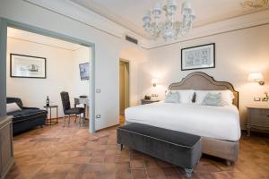 um quarto com uma grande cama branca e uma secretária em Castello Bonaria Wine & Spa Resort em Campiglia Marittima