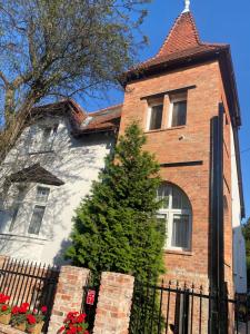 una casa di mattoni con un albero di fronte di Cherry House Apartments a Bydgoszcz