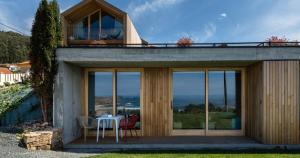 une maison avec des portes en verre, une table et des chaises dans l'établissement Doniños Nature, à La Corogne