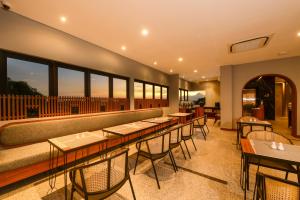 a restaurant with tables and chairs and windows at Nata Azana Hotel Solo in Solo