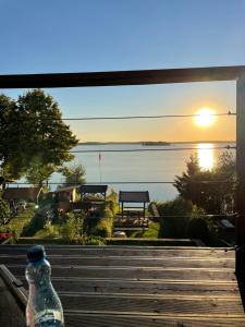 une bouteille assise sur un rebord de fenêtre avec vue sur l'eau dans l'établissement Apartamenty Fuleda nad jeziorem Dobskim Mazury Holiday, à Fuleda