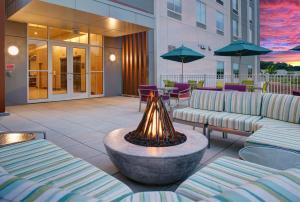 een hotelpatio met banken, tafels en parasols bij Hilton Garden Inn Manassas in Manassas