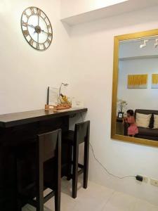 a desk with a mirror and a clock on a wall at Amara Cityland Prime Residences in Tagaytay