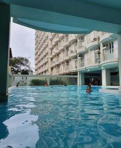 a swimming pool in front of a large building at Amara Cityland Prime Residences in Tagaytay