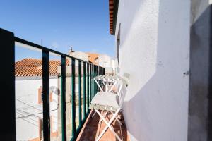 een witte stoel op het balkon van een huis bij A Casa da Marina - Sitio in Nazaré