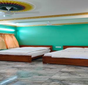 Duas camas num quarto com uma parede verde em Selva Inn em Pondicherry