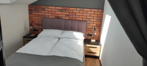 Bett in einem Zimmer mit Ziegelwand in der Unterkunft Apartamenty Comfort in Gniezno