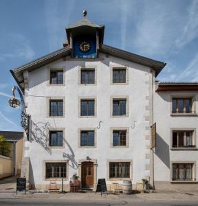 a building with a clock tower on top of it at Hôtel-Restaurant Le Cochon Rose in La Sagne