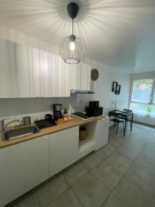 a kitchen with white cabinets and a sink and a table at Grand Studio neuf in Aulnay-sous-Bois