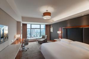 a hotel room with a large bed and a chair at Sheraton Changsha Hotel in Changsha