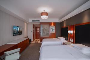 a hotel room with three beds and a tv at Sheraton Changsha Hotel in Changsha