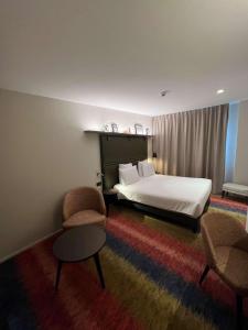 um quarto de hotel com uma cama e duas cadeiras em Mercure Fribourg Centre Remparts em Fribourg