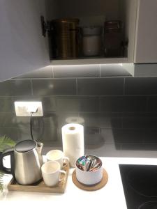 una encimera con tazas en una bandeja y un rollo de paños de papel en Apartament Patio Vita -garaż podziemny, taras,wejście klamka kod,centrum, en Kielce