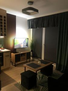 sala de estar con mesa y TV en Apartament Patio Vita -garaż podziemny, taras,wejście klamka kod,centrum, en Kielce