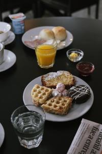 een tafel met borden met ontbijtproducten en -dranken bij Hotel Germania in Puerto Varas