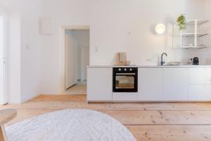 a white kitchen with white cabinets and an oven at Gran.Suite - Central Station in Sankt Pölten