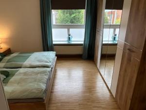 a bedroom with a bed and two windows at Ferienwohnung Stadtgracht in Nordhorn