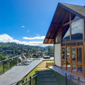 una casa con terrazza arredata con tavolo e sedie di Chalés Mirante Monte Verde a Monte Verde