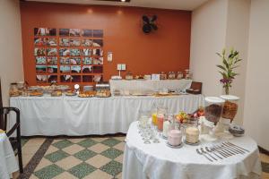 a table with white table cloths and food on it at Hotel Colonial Salta in Salta