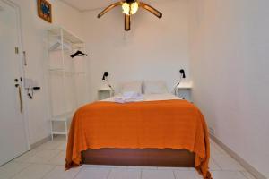 um quarto com uma cama com um cobertor laranja em Ria Beach Studio em Faro