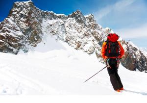 uma pessoa com uma mochila em pé numa montanha coberta de neve em Residence Nube D'Argento em Sestriere