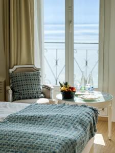 Schlafzimmer mit einem Bett, einem Tisch und einem Fenster in der Unterkunft Hotel Eden Palace au Lac in Montreux