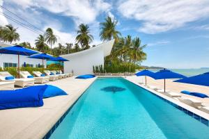 a swimming pool with lounge chairs and umbrellas at La Perle Resort Koh Samui in Mae Nam